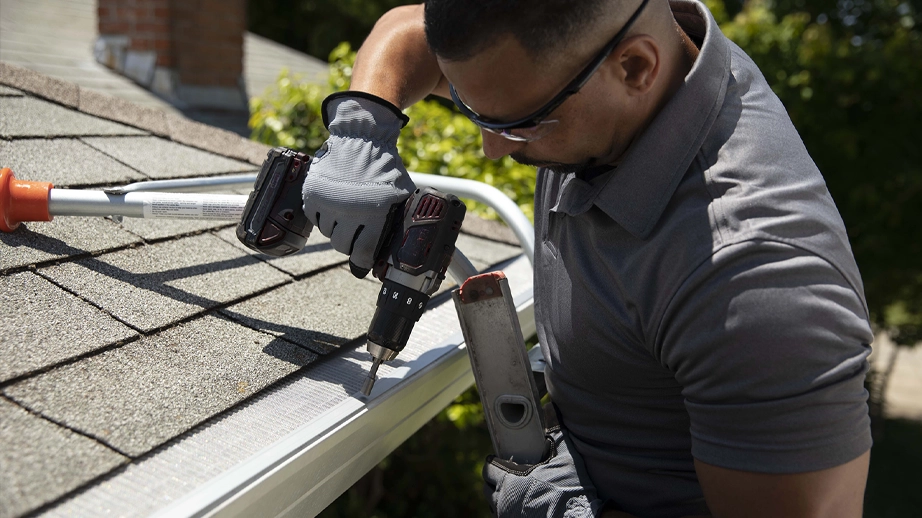 Man on ladder installing gutter guards